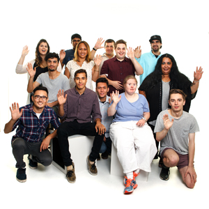 A group of diverse people sitting and standing together, raising their hands.