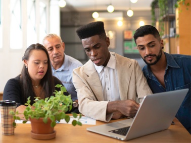 A man showing 3 people something on his computer.