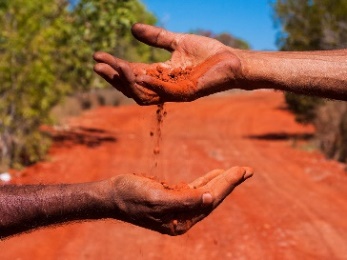 2 people holding red soil from the Australian outback.