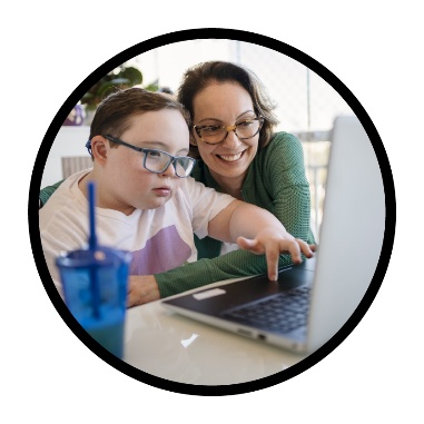 Someone supporting a child to use a laptop by themself.