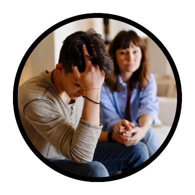 A person who looks anxious next to someone supporting them and holding their hand.