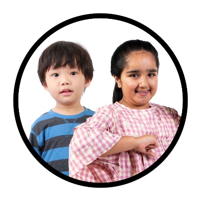 2 children, one is pointing to themself and smiling.