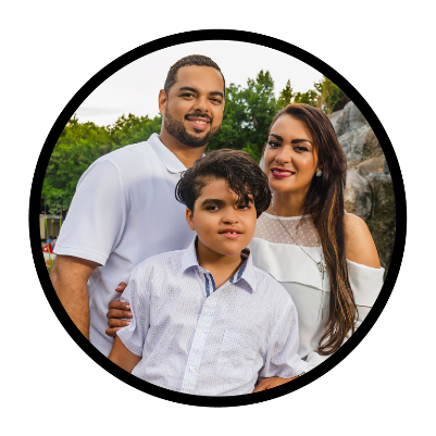 A family with 2 parents and a child who has autism. They are smiling.