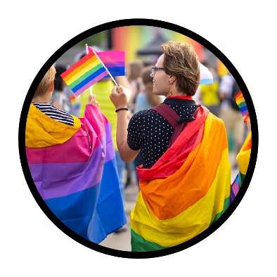 2 people wearing rainbow colours and waving rainbow flags.