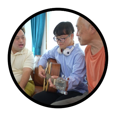 A person supporting participants to play a guitar.