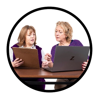 2 people looking at a document and a computer.