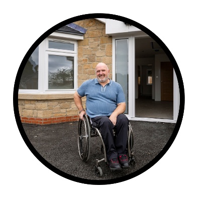 A person with disability in front of their home.
