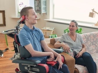 A person using a wheelchair next to someone on a couch.