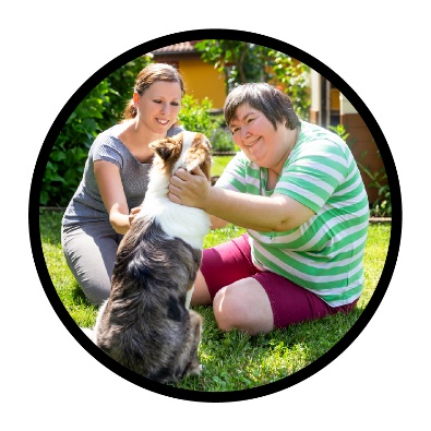 2 people petting a dog outside.