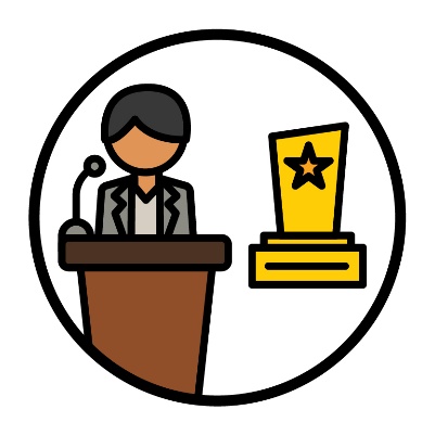 A person announcing an award. They are standing at a lectern with a microphone.