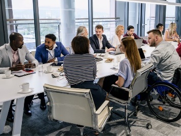 A large group of people in an office meeting at a large table.