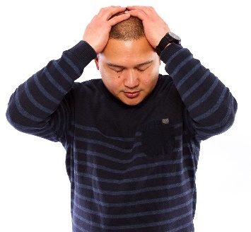 A person with their hands on their head. They look stressed.