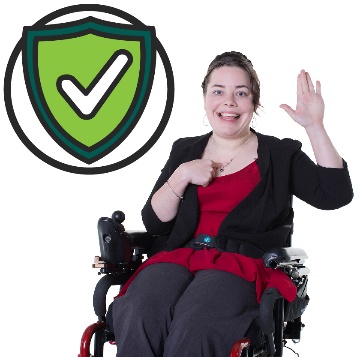 A woman in a wheelchair pointing to herself with a safety icon.