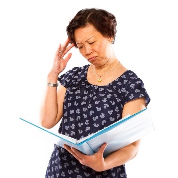 A person holding their head, reading a document. 