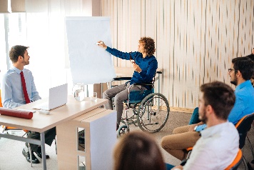 A person in a wheelchair giving a speech to a group of people. 