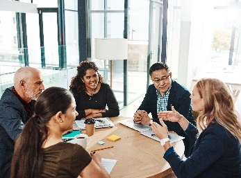 A group of people at a table in an office. They are having a meeting.