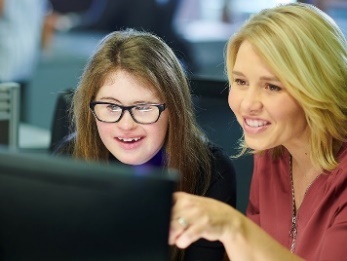 A woman showing another woman information on a computer. 