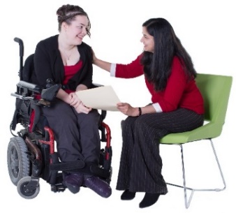 A woman explaining a document to another woman in a wheelchair.