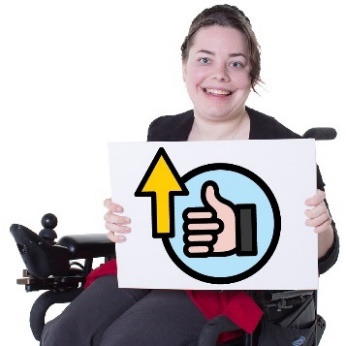 A participamt using a mobility aid holding a sign that shows a thumbs up and an arrow pointing up.