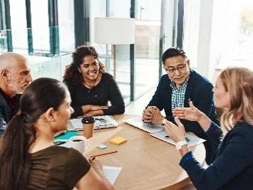 A person talking to a group of people around a table.