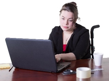 A person in a wheelchair using a computer at a desk.