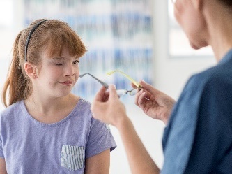 A person putting glasses on a child.