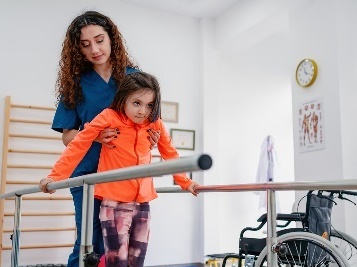 A therapist supporting a child to walk.