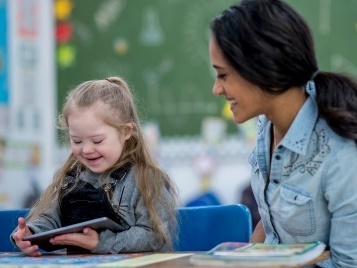A teacher supporting a young child using a digital tablet.
