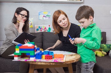 Two people listening to a child at an art and craft table. 