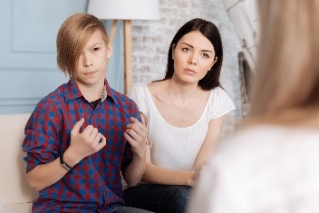 A young person talking, while two people are listening. 