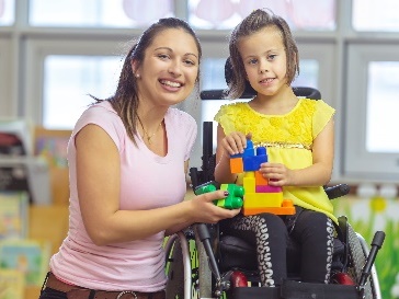 A person with a young child in a wheelchair. 