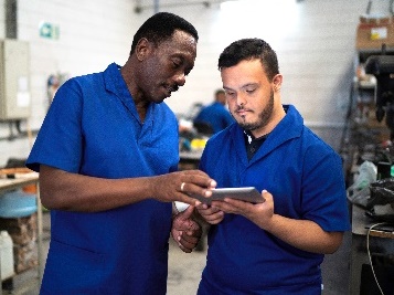 2 people in a workshop looking at a digital tablet.