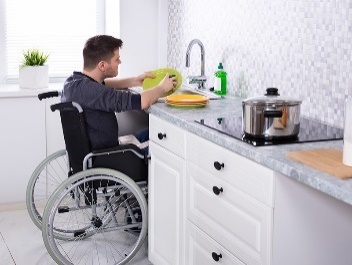 A person in a wheelchair washing dishes. 