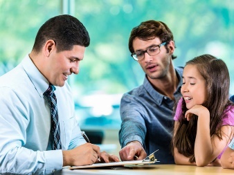 A support worker having a conversation with a parent and their child. They are filling out a document together.