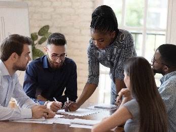 A group of people working together on documents at a desk.