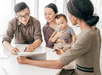 Parents with their child looking at documents that a worker is showing to them.