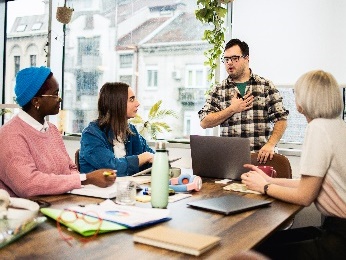 A group of people listening to someone speak in a meeting.