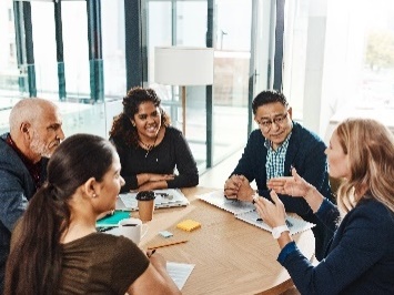 A group of people sitting at a table in a meeting. 