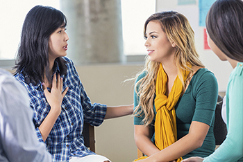 A group of people having a conversation and supporting each other.