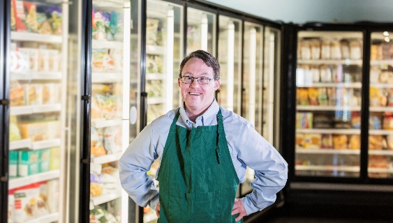 A person in an apron working at a grocery store.