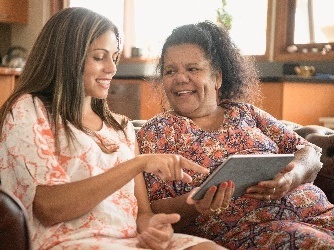 2 First Nations people looking at information on a digital tablet.