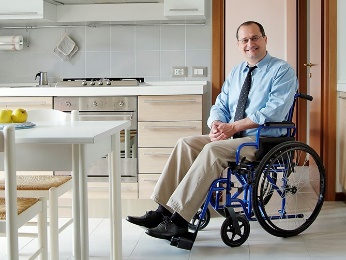 A man in a wheelchair in a kitchen. 