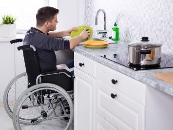 A person in a wheelchair washing dishes.