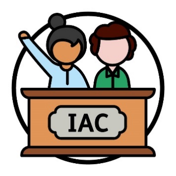 2 people behind a bench that says 'IAC' and one person has their hand raised.