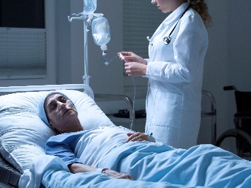 A doctor standing next to a person in a hospital bed.